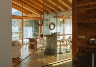 Una prestigiosa villa in bioedilizia con grandi vetrate e travi in legno a vista. 