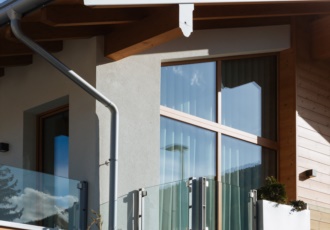 Una raffinata villa in bioedilizia con grandi vetrate e travi in legno a vista. 