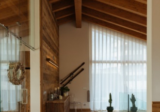 Una prestigiosa villa in bioedilizia con grandi vetrate e travi in legno a vista. 